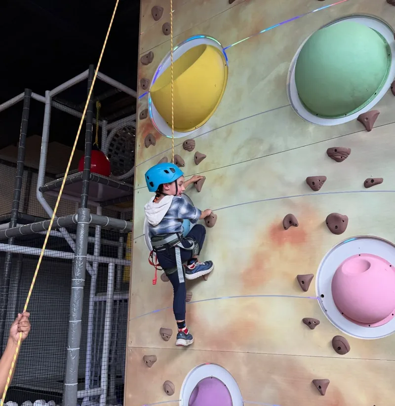 Niña con casco escalando el muro de planetas de colores
