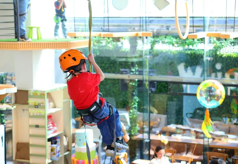 Niño con casco naranja bajando por la tirolesa